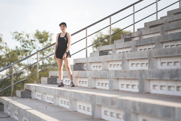 A healthy adult Asian woman running up on concrete stairs of the city stadium to strengthen body - Фото, зображення