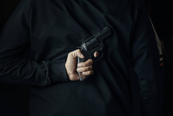 Человек с револьвером на спине. - Фото, изображение