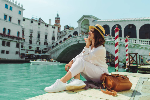 Frau sitzt in der Nähe der Rialto-Brücke in Venedig Italien Blick auf großen Kanal mit Gondeln Sommerzeit Kopierraum - Foto, Bild