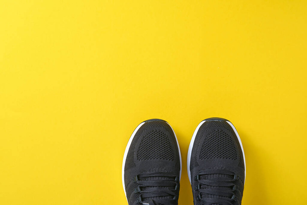 Black men sneakers on yellow background. Fashion blog or magazine concept. Men shoes, trendy sneakers, fashion, lifestyle. Mock up. Flat top view copy space minimal background. - Photo, Image