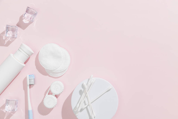 Ohrstöpsel, Wattepads, Toner (Lotion), Eiswürfel und Zahnbürste auf rosa Hintergrund. Beauty und Hygienekonzept. Hochwertiges Foto - Foto, Bild