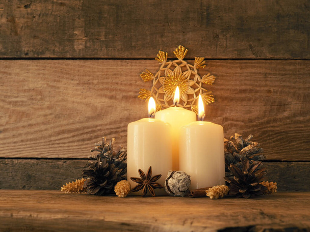 Third Advent, three candles burning on a rustic wooden table with Christmas decoration - Foto, afbeelding