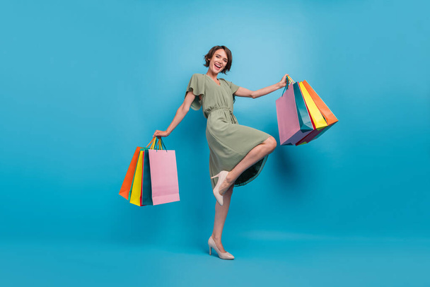 Full size photo of positive cheerful young woman hand shopping bags sale mall isolated on blue color background - Фото, зображення