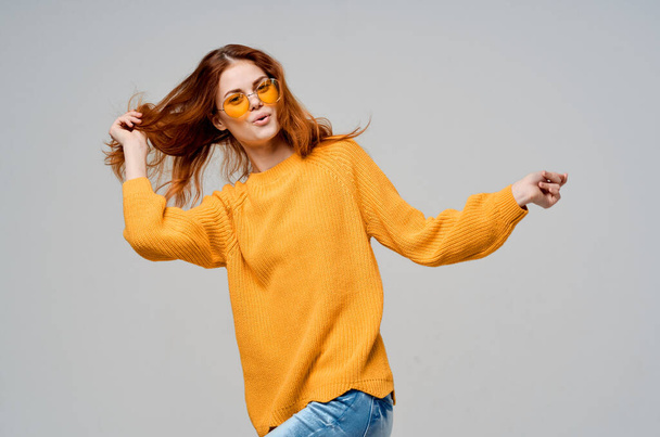κοκκινομάλλα γυναίκα σε ένα κίτρινο πουλόβερ μόδας γυαλιά στούντιο μοντέλο - Φωτογραφία, εικόνα