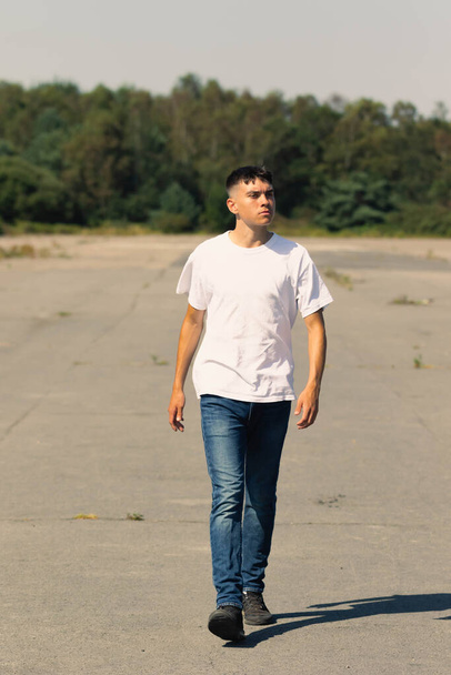 18 year old teen boy in a white t-shirt outdoors and blue denim jeans - Photo, image