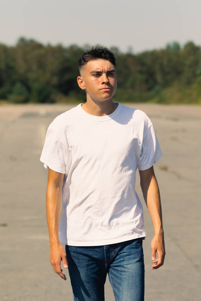 18 year old teen boy in a white t-shirt outdoors and blue denim jeans - Fotó, kép