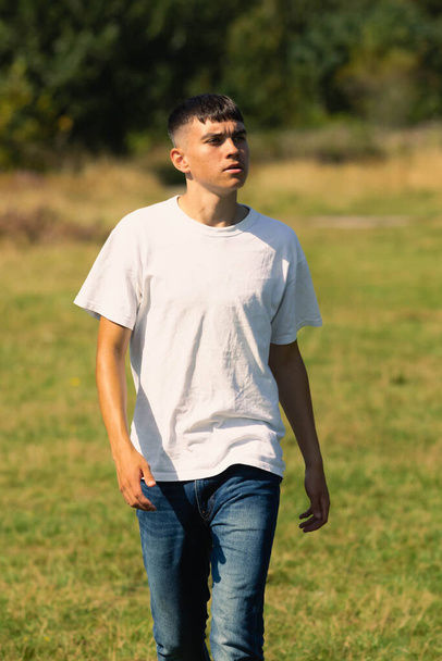 18 éves tini fiú fehér pólóban a szabadban és kék farmer farmer - Fotó, kép