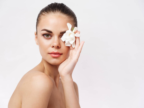 όμορφη γυναίκα γυμνοί ώμοι λευκό λουλούδι κοντά στο πρόσωπο close-up - Φωτογραφία, εικόνα