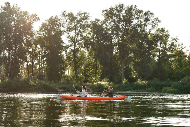 Kayak with young couple boating together on a lake surrounded by peaceful summer nature - Foto, Bild