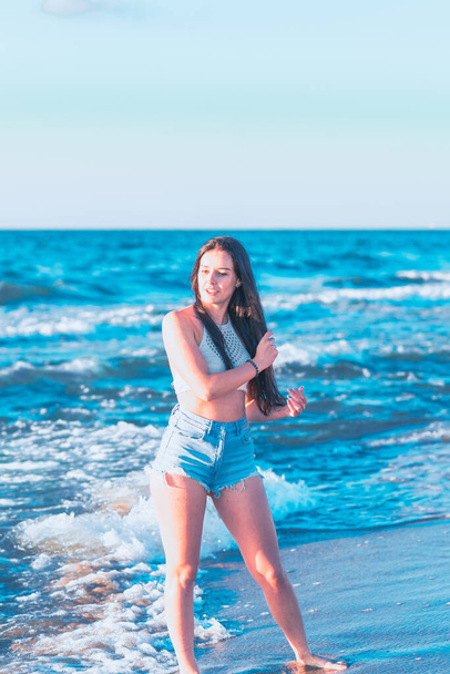 Young woman playing in the sea in summer. woman enjoying in sea water.Cheerful young woman having fun on the beach. She is relaxed in the sea water and enjoys on vacation. - Foto, Imagen