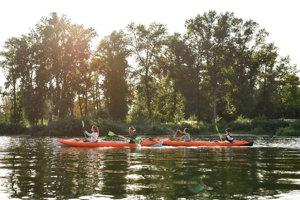 Canoe with young people boating together on a river surrounded by peaceful summer nature - Photo, Image