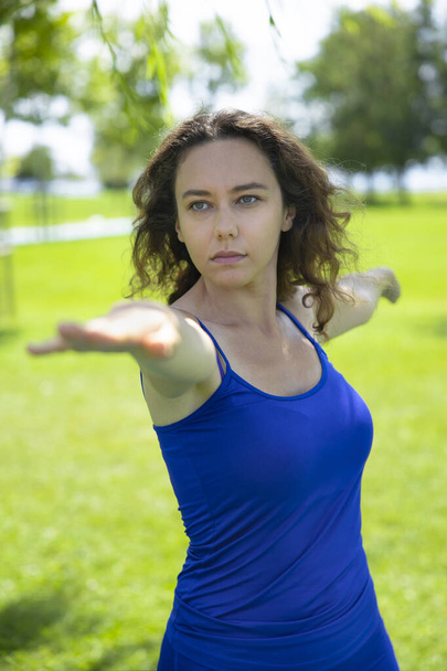 Young woman doing yoga exercise on green grass - Foto, afbeelding