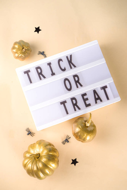 Trick or treat background, Simple Halloween greeting card, party invitation abstract flatlay with golden colored pumpkins, stars, spiders, on beige yellow background copy space top view - Foto, Imagem