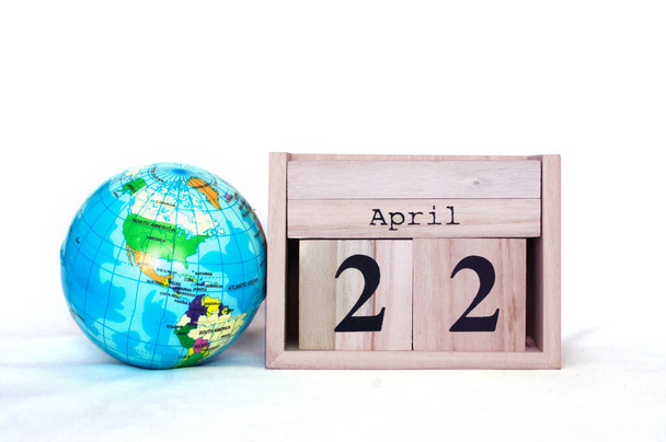houten blok kalender ingesteld op 22 april met globe naast op wit met kopieerruimte - Foto, afbeelding