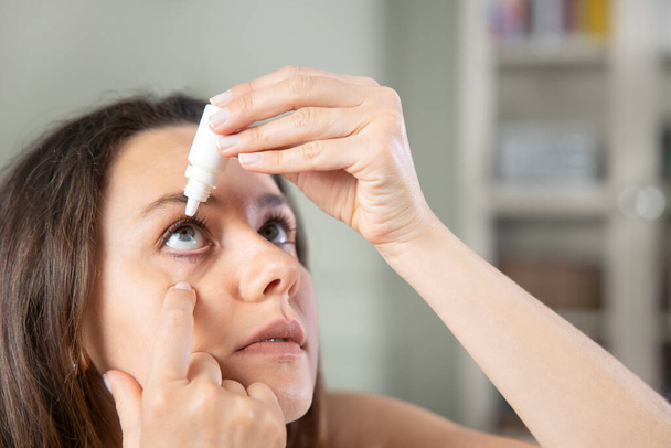 Closeup view of young woman applying eye dro - Фото, зображення