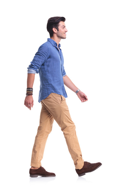 πλάγια όψη της ένας χαμογελαστός νεαρός άνδρας casual, περπάτημα - Φωτογραφία, εικόνα