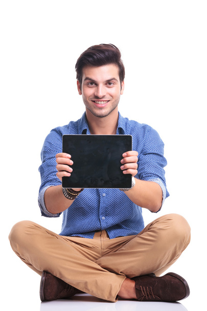 Lächelnder sitzender Mann zeigt den Bildschirm seines Tablets  - Foto, Bild