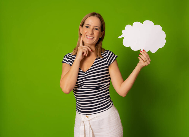 Young smiling woman in striped t-shirt holding paper cloud isolated over green background. - Photo, Image