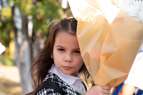 Little first-grader with a bouquet blows a kiss to her parents - Photo, Image