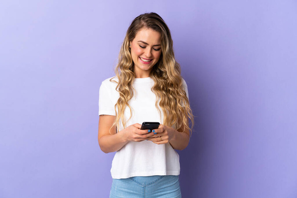 Молода бразилька, ізольована на пурпуровому фоні, відправляє повідомлення мобільним телефоном. - Фото, зображення