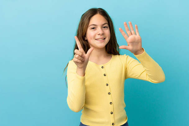 Little caucasian girl isolated on blue background counting seven with fingers - Photo, Image