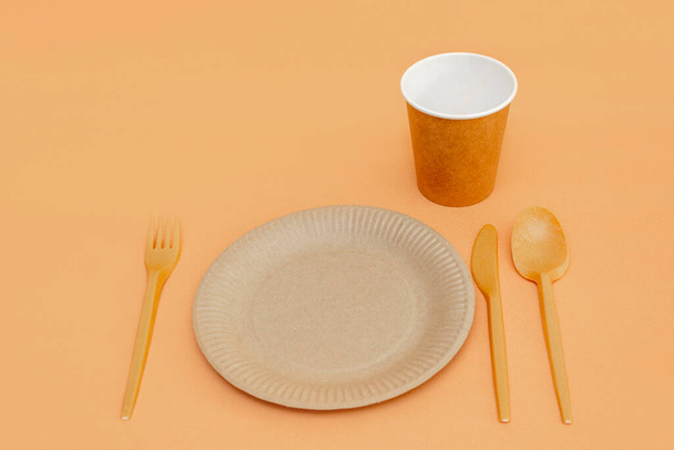 Recyclable fork, spoon, knife, plate and cup on a beige background. Kitchen utensils. Top view. Minimalist Style. Copy space. - Valokuva, kuva