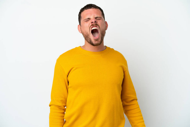 Young Brazilian man isolated on white background shouting to the front with mouth wide open - 写真・画像