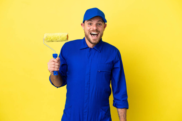 Painter Brazilian man isolated on yellow background with surprise facial expression - Zdjęcie, obraz