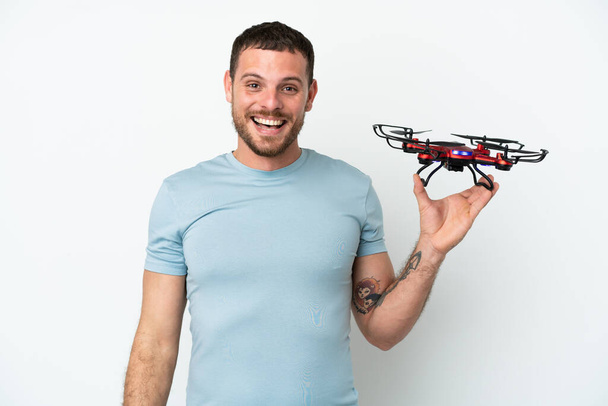 Νεαρός Βραζιλιάνος κρατώντας ένα drone απομονωμένο σε λευκό φόντο με έκφραση έκπληξη στο πρόσωπο - Φωτογραφία, εικόνα