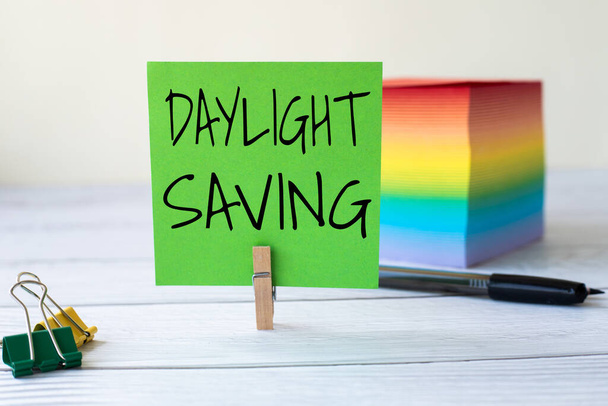 Conceptual caption Daylight Saving. Business concept turning the clock ahead as warmer weather approaches Blank Sticky Note Laundry Clip Stack Of Colorful Paper Pen Placed On Desk. - Photo, Image