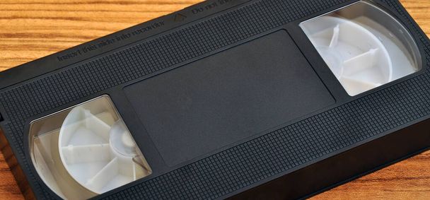 Oude blanco vhs analoge video cassette tape geïsoleerd op hout achtergrond - Foto, afbeelding