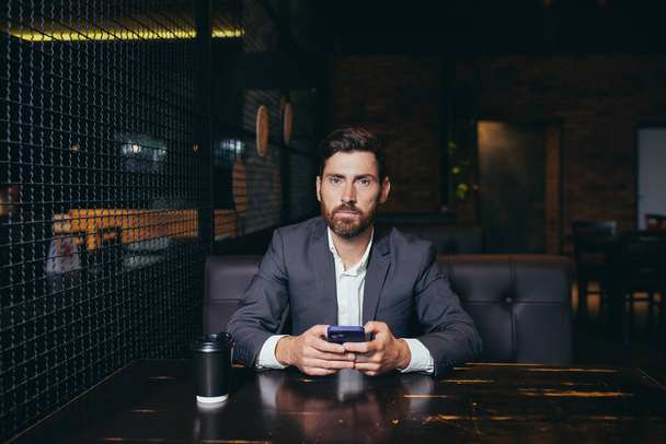 Successful bearded businessman corresponded in messenger on mobile application in restaurant - Photo, Image