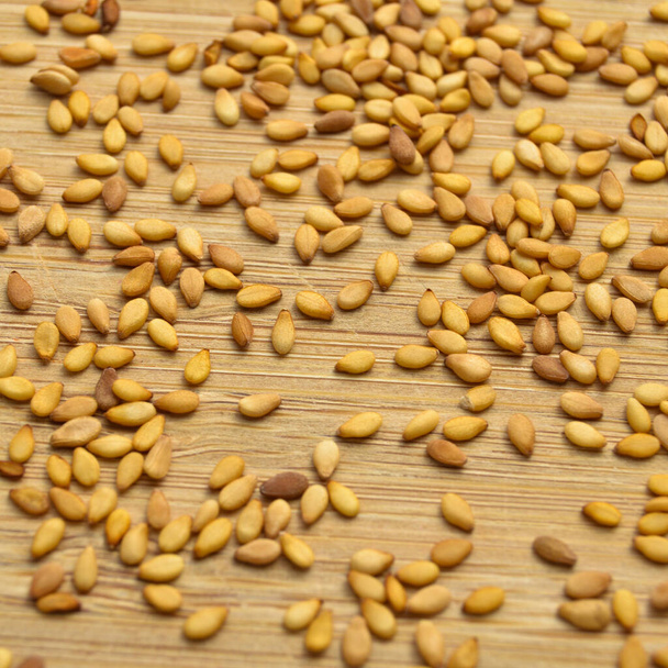 Pieczone świeże organiczne nasiona sezamu tekstury, na desce do cięcia bambusa - Zdjęcie, obraz