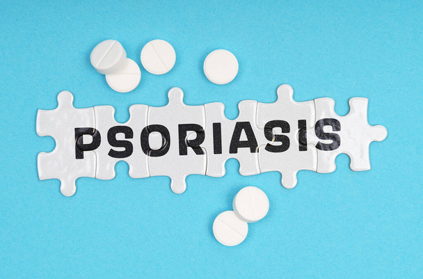 Medicine concept. On a blue background pills and puzzles with the inscription - PSORIASIS - Photo, image