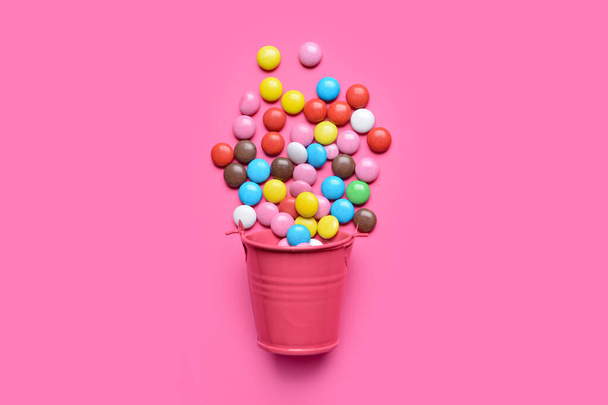 Bucket with candies on color background - Valokuva, kuva