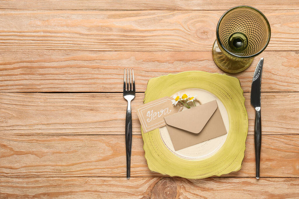 Красивая сервировка стола с ромашковыми цветами и конвертом на деревянном фоне - Фото, изображение