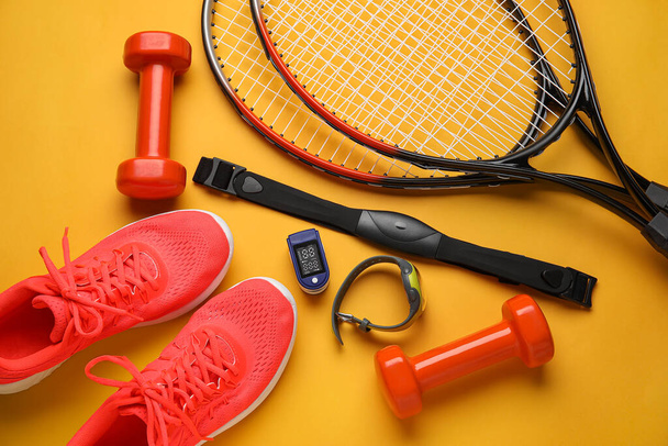 Pulse oximeter, fitness tracker, chest belt, sport shoes and equipment on color background, closeup - Photo, image