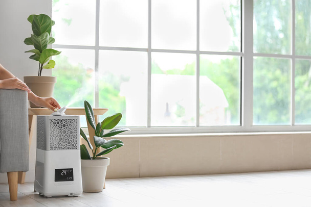 Kobieta z nowoczesnym nawilżaczem powietrza w domu - Zdjęcie, obraz