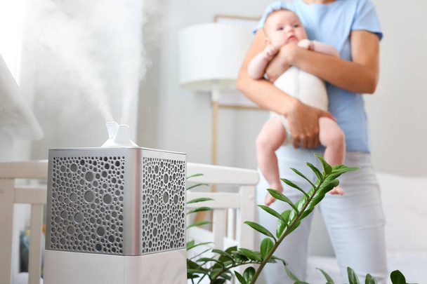 Modern humidifier in room with mother and her baby - Fotoğraf, Görsel
