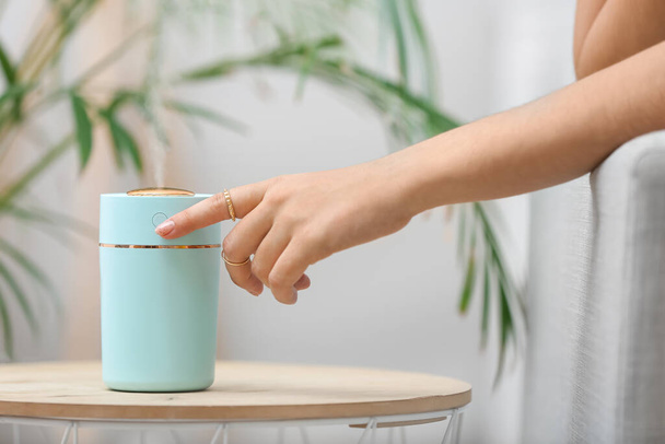 Woman switching on modern air humidifier at home - Photo, Image