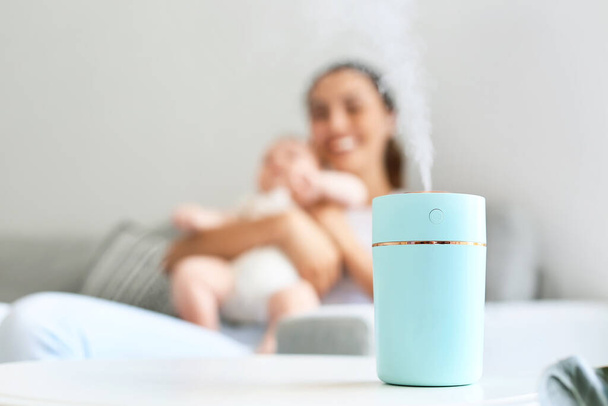 Moderne luchtbevochtiger in de kamer met moeder en haar baby - Foto, afbeelding