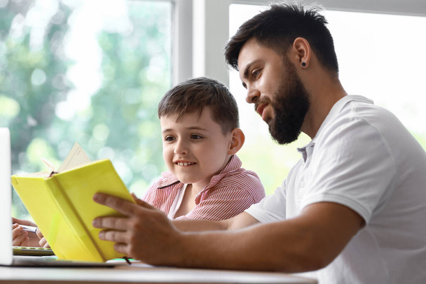 A kisfiú az apjával otthon tanul. - Fotó, kép