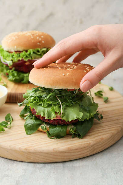 Kobieta przygotowuje smaczny wegetariański burger przy stole - Zdjęcie, obraz