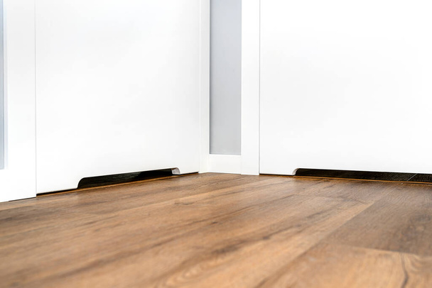 Detailní záběr bílých dveří s ventilací v moderním domě s vinylovou deskou na podlaze. - Fotografie, Obrázek