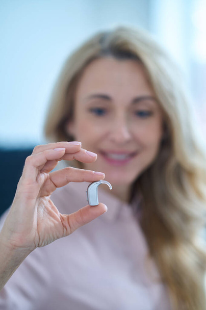 Woman looking at small hearing aid - Fotoğraf, Görsel