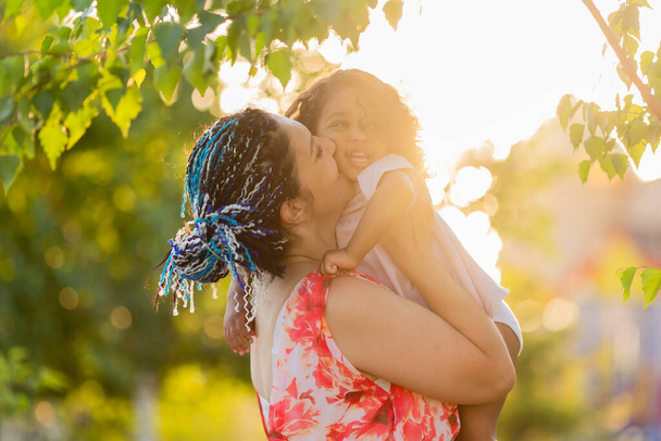 Familia multicultural. Madre e hija en el verde parque de verano  - Foto, imagen