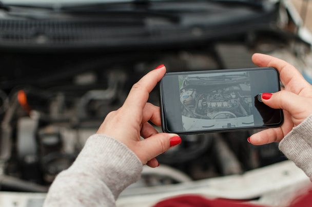 Hände einer hispanischen Frau beim Fotografieren des Motors ihres Autos - Foto, Bild