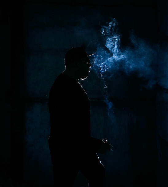 silhouette of  man smoking  cigarette on dark    background - Photo, Image