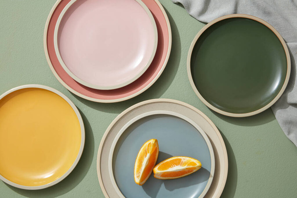 Redacción plana mínima de naranja rebanada en platos de colores con servilletas de lino. Vista superior. - Foto, Imagen