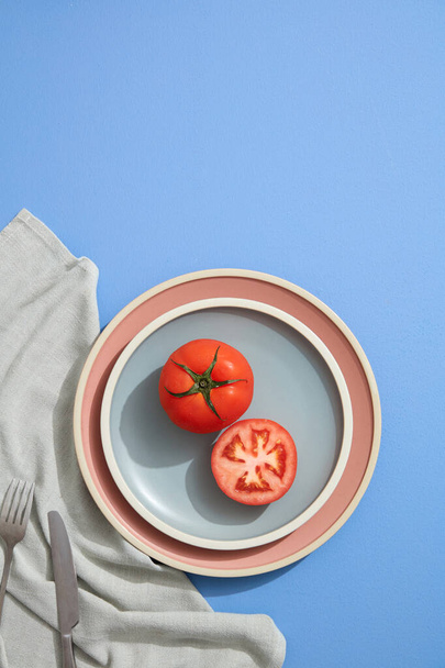 Minimal flache Tomatenlage auf pastellfarbenen Tellern mit Leinenserviette. Flache Lage, Draufsicht. - Foto, Bild